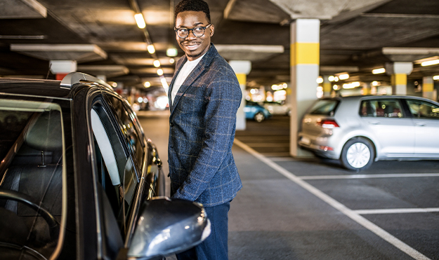 Man in suite opening car door in parking garage
