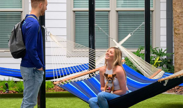 Young woman sitting in a hammock with holding a dog